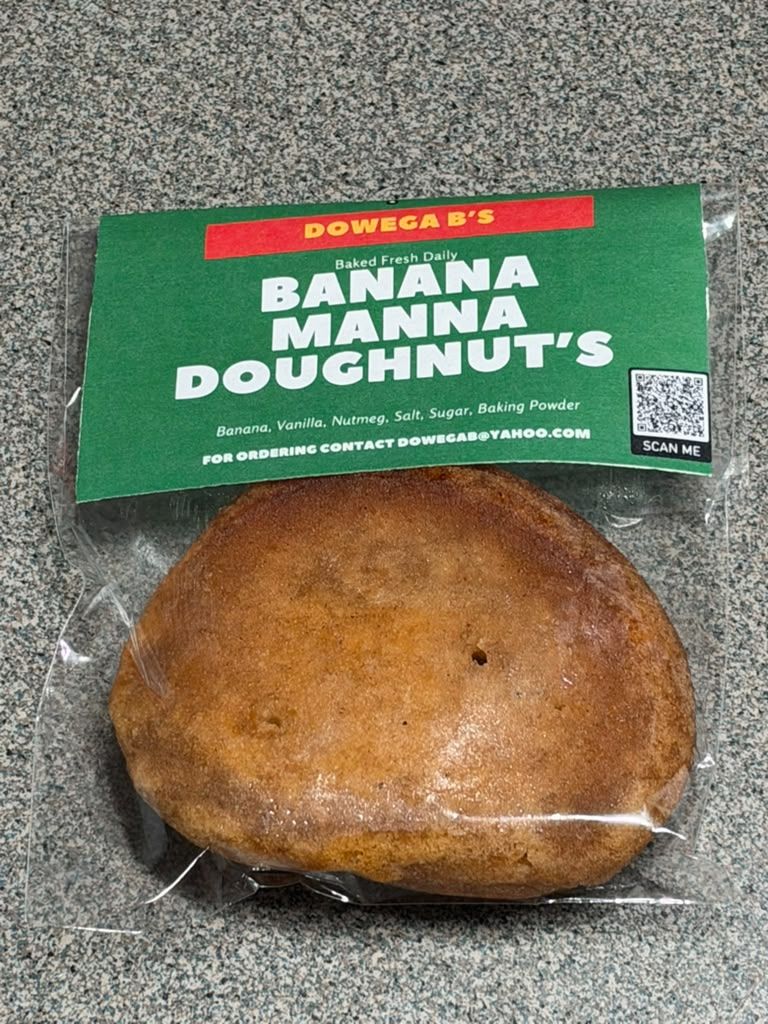 A golden banana manna doughnut sealed in a clear bag with the green Dowega B's Banana Manna label